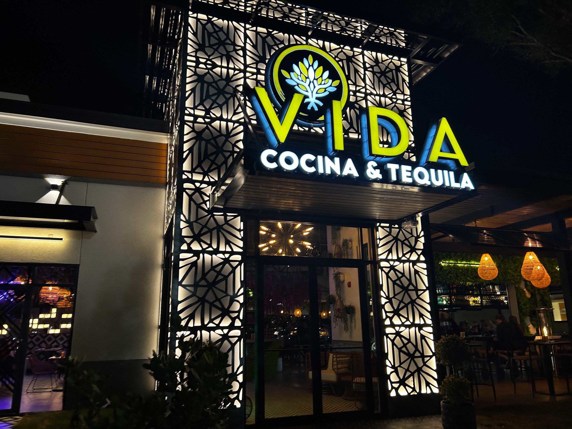 front of vida restaurant at night with yellow and blue lit up sign